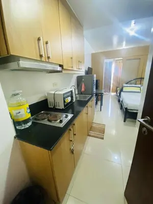 a kitchen with a counter and a room with a bed at SD 2 staycation in Manila
