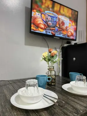 a wooden table with plates and cups and a tv at SD 2 staycation in Manila