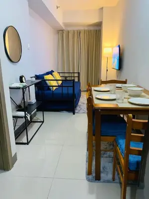 a living room with a table and a blue couch at 1 Bedroom with Balcony near Mall of Asia in Manila