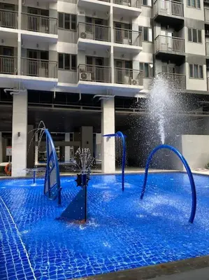 a large swimming pool with a fountain in front of a building at 1 Bedroom with Balcony near Mall of Asia in Manila