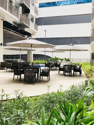 an outdoor patio with tables and chairs and umbrellas at 1 Bedroom with Balcony near Mall of Asia in Manila