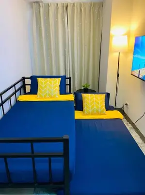 a room with two beds with blue and yellow pillows at 1 Bedroom with Balcony near Mall of Asia in Manila
