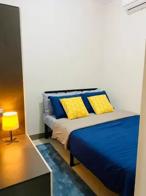 a bedroom with a bed with blue and yellow pillows at 1 Bedroom with Balcony near Mall of Asia in Manila