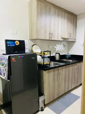a kitchen with a black refrigerator and a sink at 1 Bedroom with Balcony near Mall of Asia in Manila