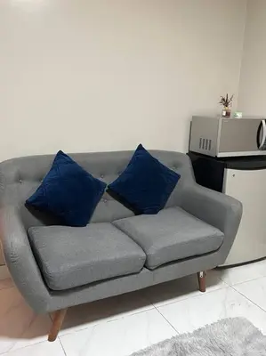 a couch with blue pillows on it in a living room at Cozy 1-BR Retreat Near MOA Pool view in Manila