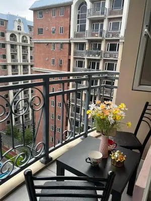 a table and chairs on a balcony with a view of a building at Cozy 1-BR Retreat Near MOA Pool view in Manila
