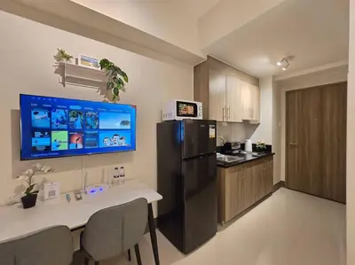 a kitchen with a table and a black refrigerator at 1BR Condotel with Balcony at FAME Residences #FM57 in Manila