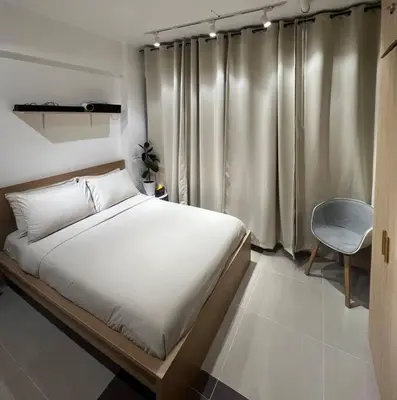 a bedroom with a white bed and a chair at Chic & Cozy Apartment Near BGC with Home Theater Setup in Manila