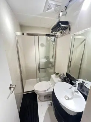 a bathroom with a toilet and a sink and a shower at Chic & Cozy Apartment Near BGC with Home Theater Setup in Manila
