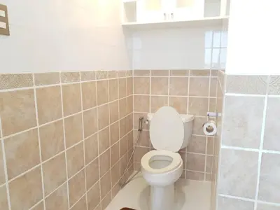 a bathroom with a toilet and a tiled wall at Alpha Grandview Malate Condo 2004 in Manila