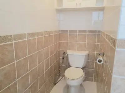 a bathroom with a toilet and a tiled wall at Alpha Grandview Malate Condo 2004 in Manila