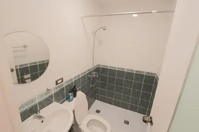 a bathroom with a toilet and a sink and a mirror at Alpha Grandview Malate Condo 2004 in Manila