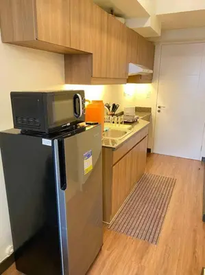 a kitchen with a microwave on top of a refrigerator at Easy Escape 1bedroom unit Satori Pasig in Manila