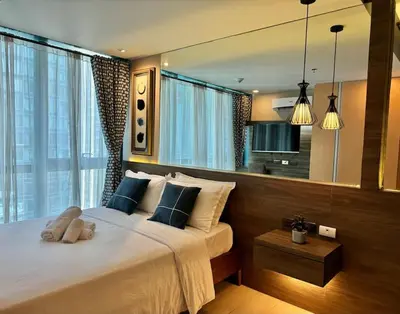 a bedroom with a large bed with a large window at Comfy 1BR At Uptown BGC in Manila