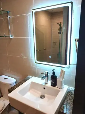 a bathroom with a sink and a mirror and a toilet at Comfy 1BR At Uptown BGC in Manila