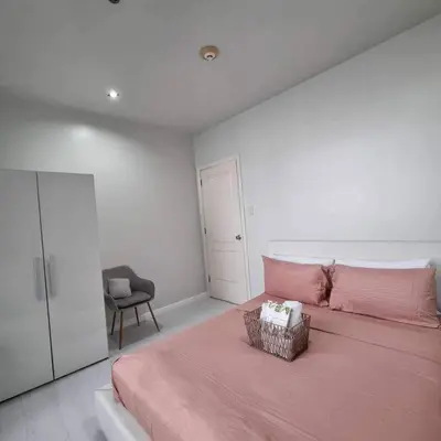 a bedroom with a pink bed and a chair at Cozy Two Bedroom Flat in The Gramercy Residences in Manila