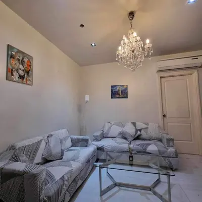 a living room with a couch and a chandelier at Cozy Two Bedroom Flat in The Gramercy Residences in Manila