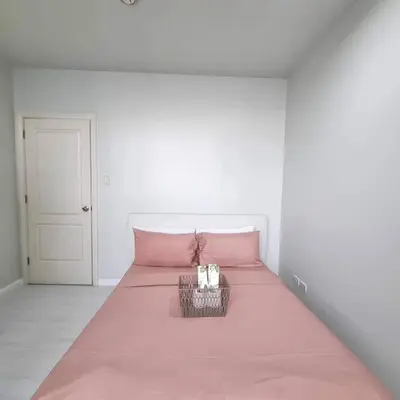 a pink bed in a white room with a pink blanket at Cozy Two Bedroom Flat in The Gramercy Residences in Manila