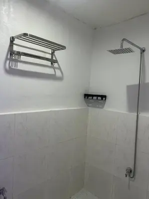 a bathroom with a shower and a white wall at ACL Staycation Home in Imus & Kawit with portable pool unit 2 in Kawit
