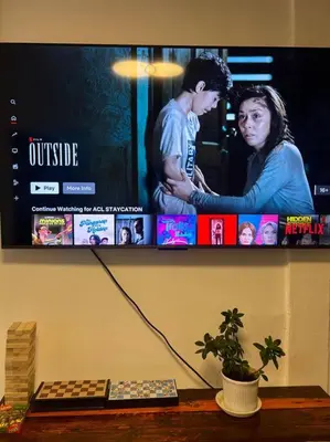 a tv on a wall above a table with a plant at ACL Staycation Home in Imus & Kawit with portable pool unit 2 in Kawit