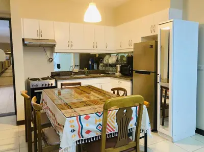 a kitchen with a table and a refrigerator at Cozy 3 Bedroom Staycation near BGC Makati Airport in Manila