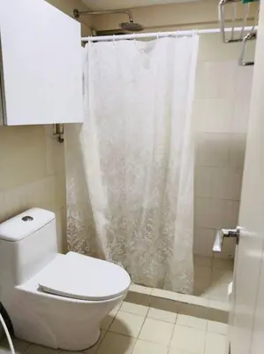 a bathroom with a white shower curtain and a toilet at Cozy 3 Bedroom Staycation near BGC Makati Airport in Manila