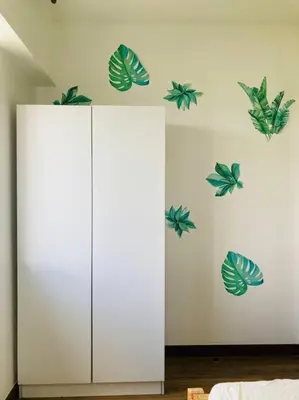 a white cabinet with green leaves on a wall at Cozy 3 Bedroom Staycation near BGC Makati Airport in Manila