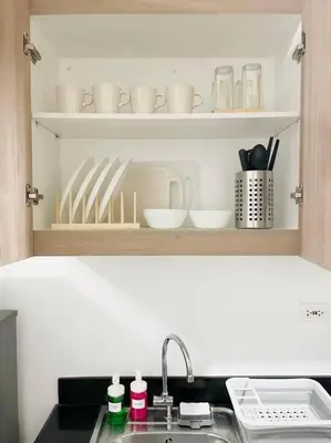 a kitchen counter with a sink and dishes on shelves at Condo at Shore 1 with Netflix in Manila