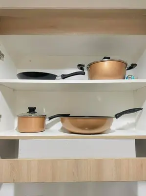 three pots and pans on a shelf in a kitchen at Condo at Shore 1 with Netflix in Manila