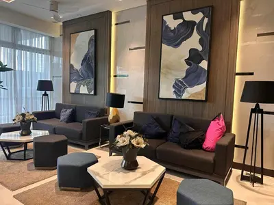 a living room with couches and tables and paintings at The Finest Charm Residences by Ashti in Manila