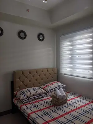 a bedroom with a bed and a window with blinds at The Finest Charm Residences by Ashti in Manila