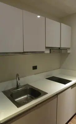 a kitchen with a sink and white cabinets at Air Residence- Makati in Manila