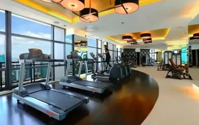 a room with a gym with cardio equipment and windows at Gramercy Century City Makati in Manila
