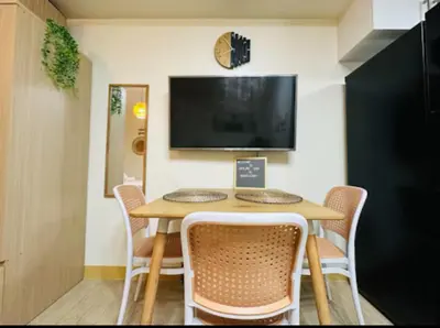 a dining room with a table with chairs and a tv at Skyline Stay in Manhattan in Manila