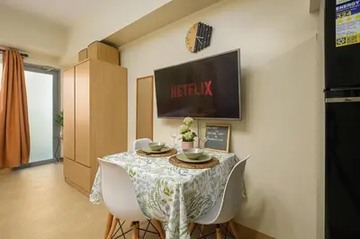 a dining room with a table and white chairs at Skyline Stay in Manhattan in Manila