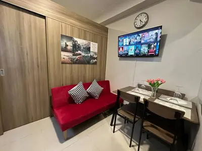a living room with a red couch and a table at Vince Cozy Staycation in Manila
