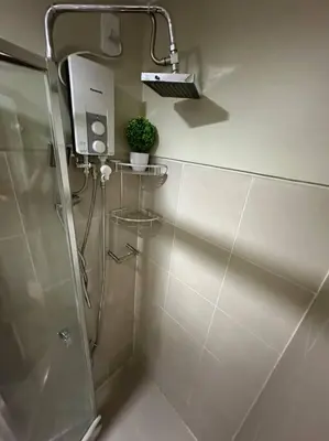 a bathroom with a shower and a plant on the wall at Vince Cozy Staycation in Manila