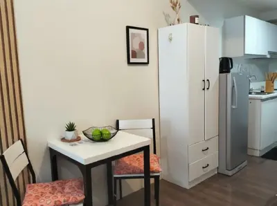 a small kitchen with a table and a refrigerator at Central Makati CBD in Manila