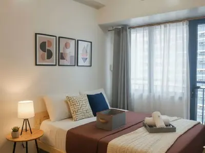 a bedroom with a large bed with a window at Heart of Makati in Manila