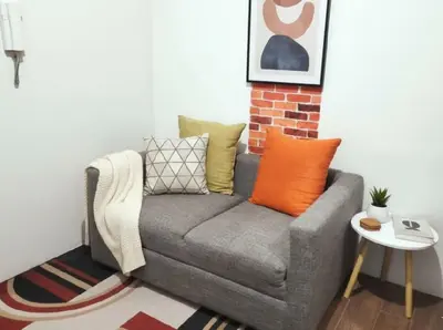 a grey couch with colorful pillows in a living room at Heart of Makati in Manila