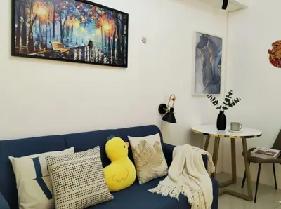 a living room with a blue couch with a yellow duck pillow at Heart of Makati in Manila