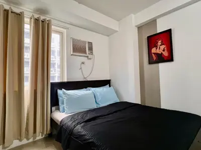 a bedroom with a bed and a window at Cozy Home in Mall of Asia - Aseana Pasay in Manila