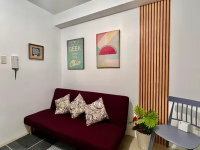 a living room with a red couch with three pillows at Cozy Home in Mall of Asia - Aseana Pasay in Manila