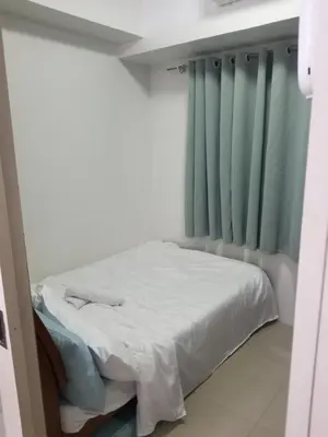 a small bed in a room with blue curtains at SEA RESIDENCES AFFORDABLE STAYCATIONs in Manila