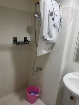 a bathroom with a shower with a sink and a bucket at SEA RESIDENCES AFFORDABLE STAYCATIONs in Manila
