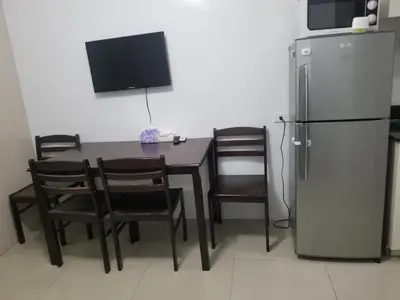 a dining room with a table and a refrigerator at SEA RESIDENCES AFFORDABLE STAYCATIONs in Manila