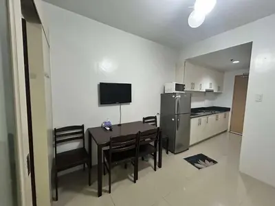 a kitchen with a table with chairs and a refrigerator at SEA RESIDENCES AFFORDABLE STAYCATIONs in Manila