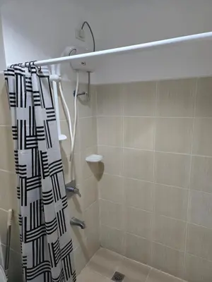 a shower with a black and white shower curtain in a bathroom at Staycation near US Embassy in Manila