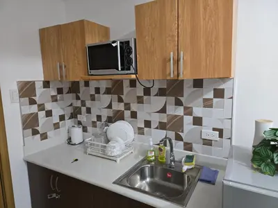 a kitchen with a sink and a microwave at Staycation near US Embassy in Manila