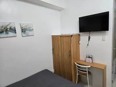 a bedroom with a bed and a tv on a wall at Staycation near US Embassy in Manila